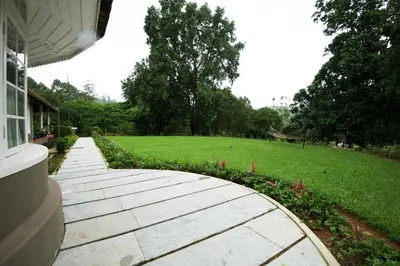 a walkway outside of a house with a grass field at Sirukundra Garden Bungalow in Vālpārai