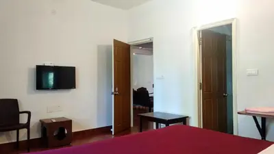 a bedroom with a bed and a tv on the wall at Heights Farm Stay - Coffee Estate Stay in Madikeri