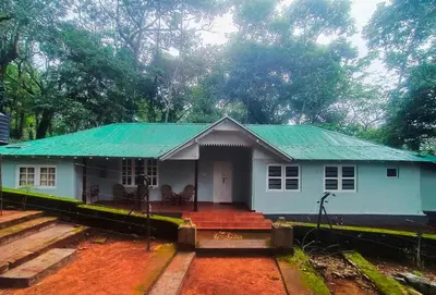a small white house with a green roof at Puthuthottam Annexe in Vālpārai