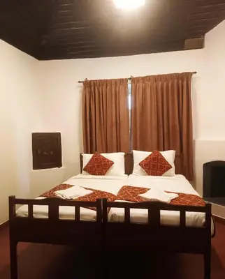 a bedroom with a bed with white sheets and pillows at Puthuthottam Annexe in Vālpārai