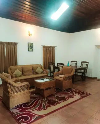 a living room with wicker furniture and a table at Puthuthottam Annexe in Vālpārai