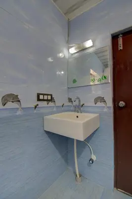a bathroom with a sink and two dolphins on the wall at Srinikethana Home Stay with Swimming Pool in Madikeri