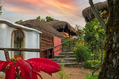 a building with stairs and thatched roofs and a building at Deshadan Eco Valley Resort - An Eco friendly Mud House in Kanthalloor