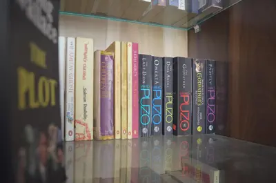 a row of books sitting on a book shelf at Blackroots Serviced Apartments in Coimbatore