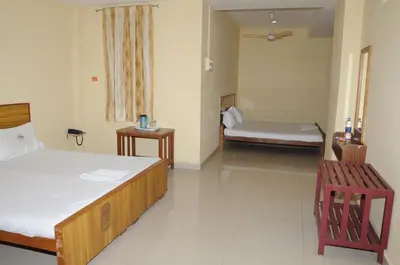 a room with two beds and a bench in it at Hotel Chanma International in Coimbatore