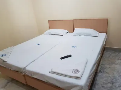a bed with white sheets and a remote control on it at Hotel Chanma International in Coimbatore
