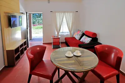 a living room with a table and chairs and a couch at Ottway Hills Mattupetty Dam in Munnar