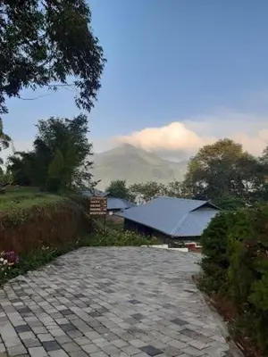 a stone walkway with a building and a mountain at Ottway Hills Mattupetty Dam in Munnar