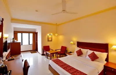 a hotel room with a bed and a table and chairs at Issacs Residency in Munnar