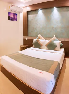 a bedroom with a large bed with white sheets and pillows at Aishwarya Le Royal in Mysore