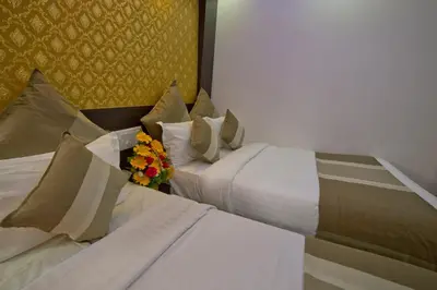 two beds in a hotel room with a bouquet of flowers at Aishwarya Le Royal in Mysore