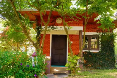 a small red brick house with a black door at Chalets Resort Masinagudi in Ooty