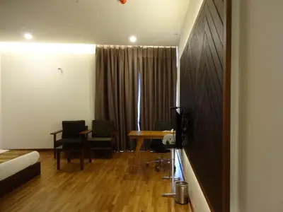 a room with a table and two chairs and a desk at Woodies Bleisure Hotel in Kozhikode