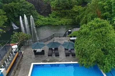 a swimming pool with a waterfall in the background at Athirapally Green Trees in Athirappilly