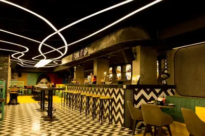 a restaurant with a bar with tables and chairs at M Inn in Coimbatore