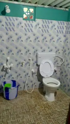 a bathroom with a white toilet with a hose at Green Hills Farm And Guest House in Masinagudi