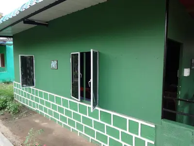 a green building with three windows on the side of it at Green Hills Farm And Guest House in Masinagudi