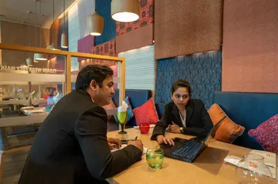 a man and woman sitting at a table with a laptop at Welcomhotel by ITC Hotels, RaceCourse, Coimbatore in Coimbatore
