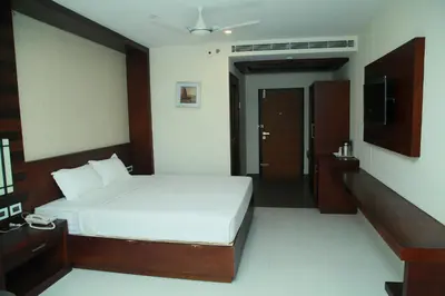 a bedroom with a white bed and a television at Vavas Inn & Suites in Perintalmanna