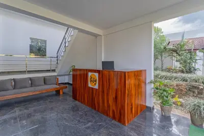 a living room with a couch and a podium with a television at Itsy Hotels Jammabane Cottage, 5 Minutes To Mountain View Coffee Plantation in Madikeri