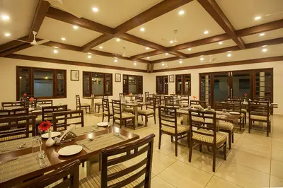 a restaurant with tables and chairs in a room at Le Coffee Resort in Sultan Bathery