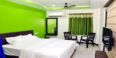 a green bedroom with a bed and two chairs at Sara Regency in Palani