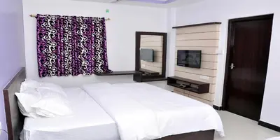 a bedroom with a white bed and a mirror at Sara Regency in Palani
