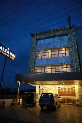 a lit up building with cars parked in front of it at Alfa Inn in Nedumbassery