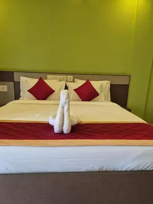 a white stuffed animal laying on a bed at Alfa Inn in Nedumbassery