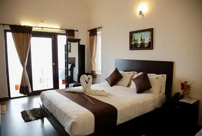 a bedroom with a large bed with a large window at Paradise Perfect - Nonsmoking Non alcoholic No unmarried couples in Ooty