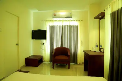 a bedroom with a chair and a desk and a window at Hotel Horizon International in Guruvāyūr
