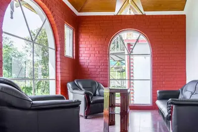 a red brick room with chairs and windows at Pine View Stay Ooty in Ooty