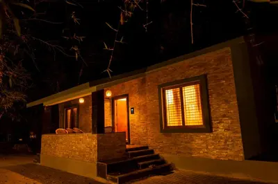 a small brick house at night with a window at MC Resort Wildlife Resort Bandipur in Bandipūr