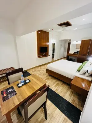 a large bedroom with a bed and a dining table at Queens Tourist Home in Badagara