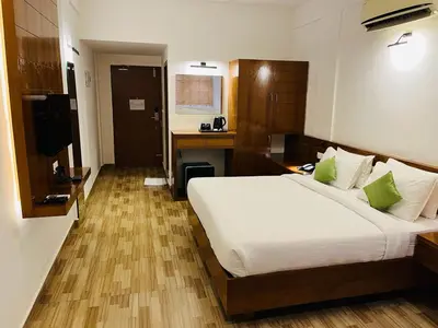 a bedroom with a large white bed and a desk at Queens Tourist Home in Badagara