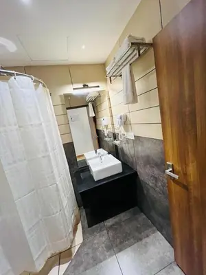 a bathroom with a sink and a white shower curtain at Queens Tourist Home in Badagara
