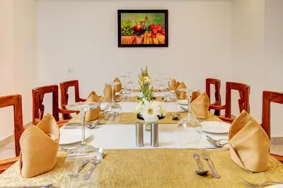 a dining room with a table with glasses and chairs at Sterling Guruvayur in Guruvāyūr