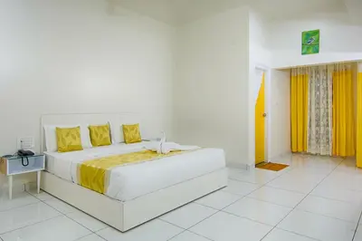 a white bedroom with a large bed with yellow pillows at The Cocoon in Gonikoppal