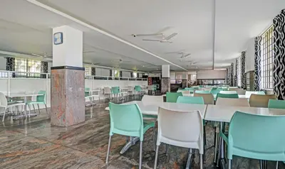 a dining room with white tables and green chairs at Treebo Green Land Coorg in Kushālnagar