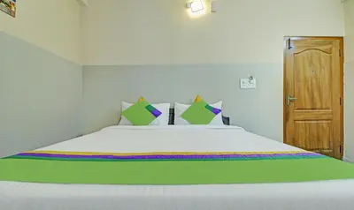 a bedroom with a large bed with green and white sheets at Treebo Green Land Coorg in Kushālnagar