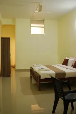 a bedroom with a bed with a chair and a window at Wayanad Royal Stream in Kalpetta