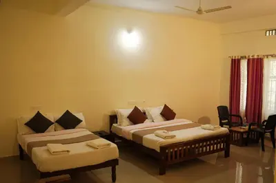 a room with two beds and a table and chairs at Wayanad Royal Stream in Kalpetta