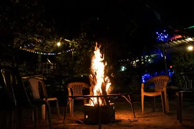 a fire pit with chairs around it at night at Wayanad Royal Stream in Kalpetta