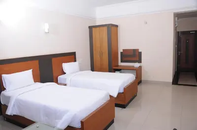 a hotel room with two beds and a desk at Alhind Calicut Tower in Kozhikode