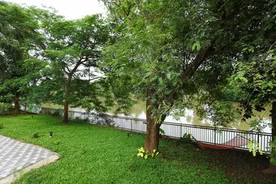 a park with a tree and a hammock in the grass at Nadhiyoram River Retreat in Cochin