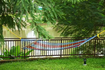 a hammock hanging on a fence next to a river at Nadhiyoram River Retreat in Cochin