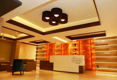 a living room with a table and chairs and a ceiling at Hotel Span in Kozhikode
