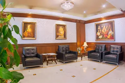a waiting room with chairs and paintings on the wall at President Hotel in Mysore