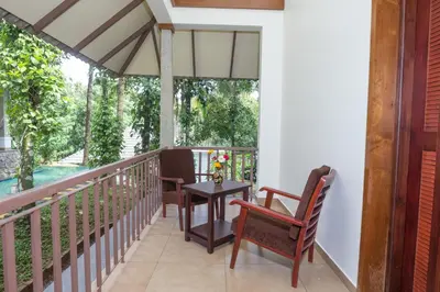 a balcony with chairs and a table and an umbrella at Century Village Resort in Mananthavady