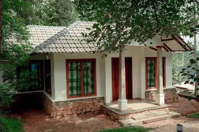 a small house with red windows in a yard at Century Village Resort in Mananthavady